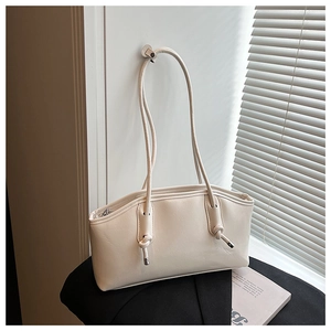 Detail of cream white leather shoulder bag with cylinder straps and metal hardware tips