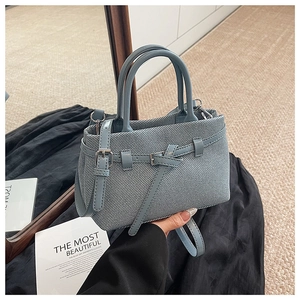 Close-up of light blue woven texture handbag with silver hardware and adjustable strap