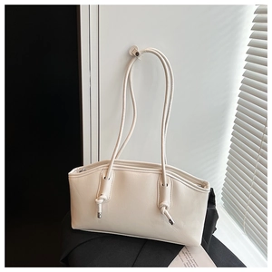 Detail of cream white faux leather shoulder bag featuring knotted strap and metal eyelets