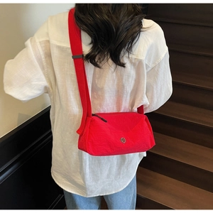 Detailed back view of a red nylon crossbody bag showing the wide strap and metal logo
