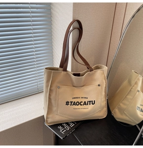 Detail view of large canvas tote bag with leather straps and printed front pocket