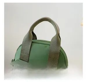 Detail view of durable green nylon handbag featuring reinforced straps and metal zippers