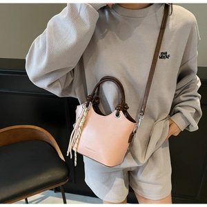 Détail du sac seau en cuir rose avec poignées contrastées et foulard en soie à carreaux