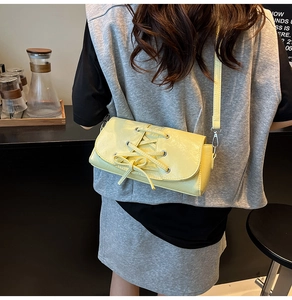 Detail of soft yellow PU leather shoulder bag with decorative bow and slim strap