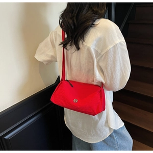 Close-up of red nylon crossbody bag with metallic M logo and wide shoulder strap
