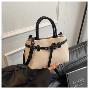Detail of beige canvas bucket bag with black leather trim and metal buckle adjustment