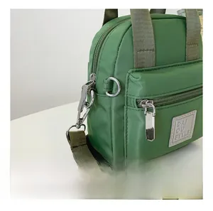 Detail of fruit green nylon bag with olive strap and polished silver metal swivel hook