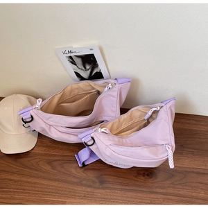Detail view of large and small light purple nylon dumpling bags on a wooden table