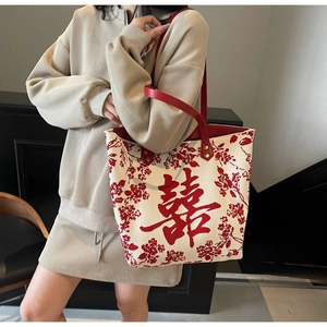 Detail of embroidered Double Happiness pattern and red leather handles on a white tote bag