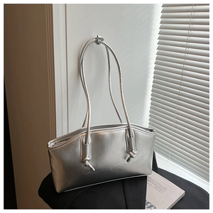 Close-up of silver shoulder bag with metallic finish and stylish knot strap detail