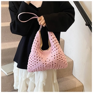 Detail of pink hand-knit hollow hobo bag with textured pattern and slim leather handle