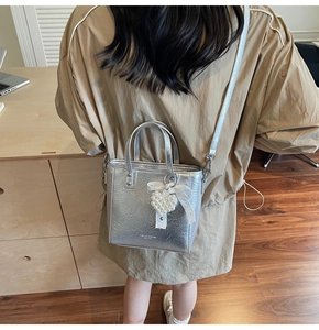 Détail d'un sac seau argenté avec breloque cœur en perle et nœud en soie décoratif