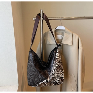 Detail of large leopard print tote bag with brown nylon strap hanging on metal hook