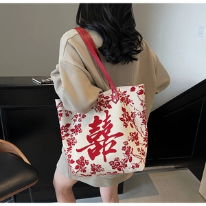 Detail of red floral embroidery and Xi character on large fabric tote bag for bride