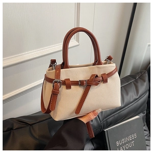 Detail of cream woven canvas bucket bag with brown leather trim and metal buckle