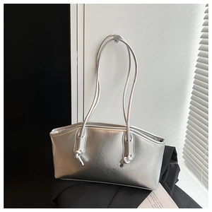 Close-up of a silver metallic tote bag with decorative knot detail and zipper closure