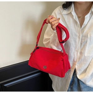 Detail of red nylon crossbody bag with metal M logo and adjustable wide shoulder strap