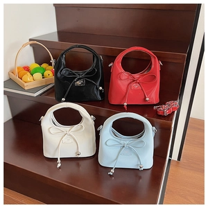 Détails de quatre sacs à main en cuir PU colorés avec nœuds sur un escalier en bois