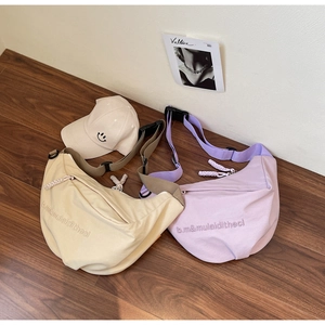 Detail of beige and lilac canvas crescent bags with adjustable straps and embroidery