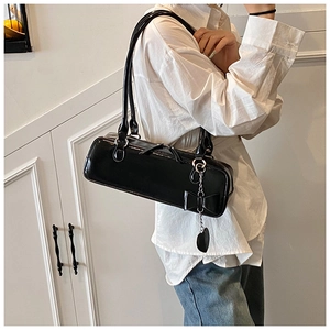 Detail of black baguette shoulder bag with silver heart and bow charms on smooth leather