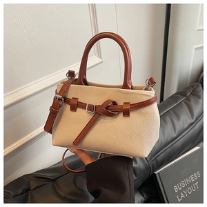 Detail of canvas bucket bag with brown leather trim and detachable shoulder strap