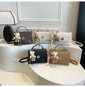 Five assorted colors of leather crossbody bags with cute plush bear charms on display
