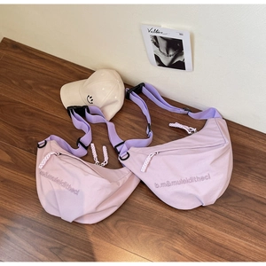 Detail view of two lilac nylon crescent moon bags with adjustable straps on wooden floor