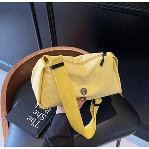 Detail shot of yellow nylon shoulder bag with adjustable strap and metallic M logo
