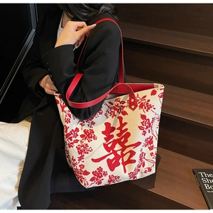 Detail of floral canvas tote bag featuring red double happiness symbol and leather handles