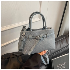 Detail of blue-grey herringbone woven bucket bag with leather straps and metal buckle