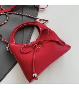 Détail du sac rouge avec nœud en cuir et bandoulière en chaîne métallique au style élégant