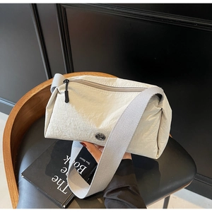 Detailed view of cream nylon crossbody bag with pleated texture and metal logo