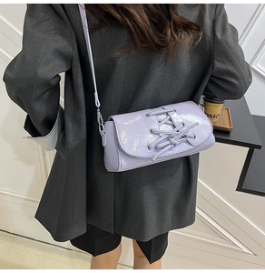 Detail of light purple glossy shoulder bag with lace-up design and silver metal hardware