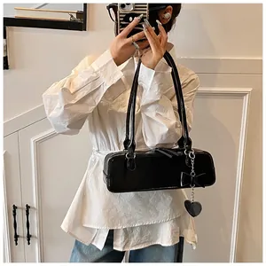 Close-up of black baguette bag with bow detail and heart pendant on metal chain strap