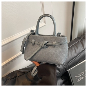 Detail of light blue bucket bag showing textured fabric and leather strap with decorative knot