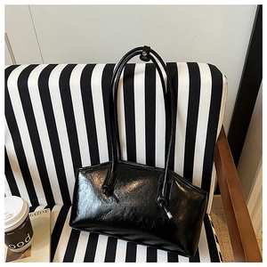 Close-up of black glossy patent leather tote bag with thin straps on a striped chair