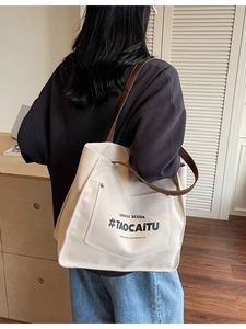 Minimalist canvas tote bag with brown leather straps shown on model in home office