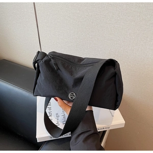 Detail of black nylon cylinder crossbody bag with silver M logo and woven strap