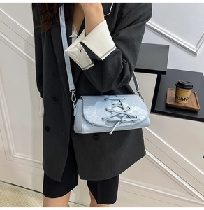 Detail of light blue patent leather shoulder bag featuring unique criss-cross strap design