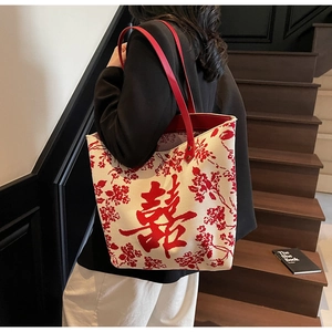 Detail view of canvas tote bag with red floral patterns and Chinese Xi character