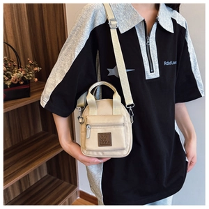 Detailed view of beige waterproof nylon crossbody bag worn by model in a casual setting