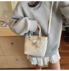 Vue détaillée du sac cabas en cuir crème avec breloque en perles et bandoulière réglable