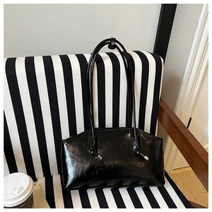 Chic black patent leather tote bag on striped chair with coffee and magazines