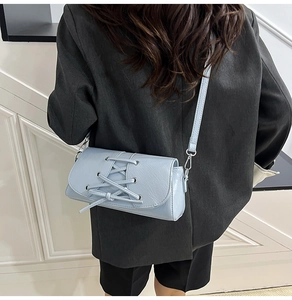 Detail view of light blue crossbody bag with unique lace-up design and metal eyelets