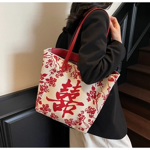 Detail view of canvas tote bag with red Double Happiness character and floral embroidery