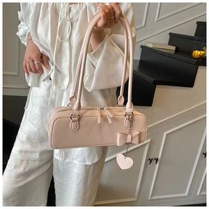Detail of light pink baguette bag featuring double zippers and a heart charm pendant