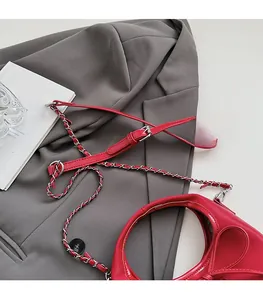 Détail du sac à main rouge avec poignée ronde creuse et bandoulière en chaîne métallique