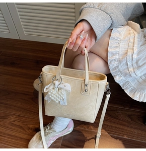 Détail du petit sac plissé crème avec breloque cœur en perle et nœud en dentelle chic