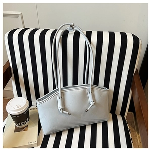 Detail of light blue leather tote bag with knotted strap on a striped chair background