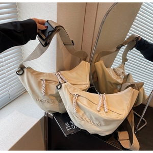 Detail of beige crescent bag showing embroidery and woven zipper on textured fabric